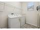 This laundry room includes shelving, a window, and a white washer and dryer unit at 5512 Solterra Cir, Davenport, FL 33837