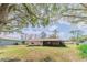 Expansive backyard with green lawn, mature trees, and a screened porch attached to the house at 6449 Eve St, St Cloud, FL 34771