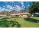 Charming single-story home featuring a lush green lawn and neatly landscaped garden beds beneath a cloudy blue sky at 6449 Eve St, St Cloud, FL 34771