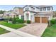 Two-story home featuring a paver driveway, two-car garage, manicured lawn, and colorful landscaping at 6974 Trellis Vine Loop, Windermere, FL 34786