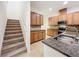 Kitchen features wood cabinets, granite countertops, and stainless steel appliances adjacent to carpeted stairs at 6974 Trellis Vine Loop, Windermere, FL 34786