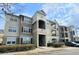 Modern condominium exterior with tan siding, red shutters, and well-maintained landscaping under a blue sky at 8137 Claire Ann Dr # 203, Orlando, FL 32825