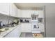 Bright kitchen with white cabinets, gray laminate flooring and granite countertops and stainless steel refrigerator at 1006 San Domingo Rd, Orlando, FL 32808