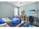 Well-lit bedroom with blue color scheme, dresser, desk, a tv, and a window with curtains at 2559 Eagle Bay Blvd, Kissimmee, FL 34743