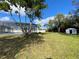 A large backyard with screened-in pool and storage shed surrounded by lush greenery at 305 S Palm Ave, Kissimmee, FL 34741
