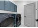 Modern laundry room featuring sleek, navy cabinets and front-load washer and dryer at 33 Perch Dr, Kissimmee, FL 34759
