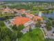Aerial view capturing the red-tiled rooftops of community buildings surrounded by lake views and lush greenery at 4311 Via Cavour Ct, Kissimmee, FL 34759