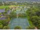 An aerial view of well-maintained tennis courts in a community surrounded by verdant trees and landscaped grounds at 4311 Via Cavour Ct, Kissimmee, FL 34759