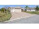 Inviting single-story home featuring a large brick driveway, manicured lawn, and a two-car garage at 4311 Via Cavour Ct, Kissimmee, FL 34759