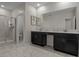 Modern bathroom with double vanity, sleek black cabinets, glass enclosed shower, and tile floors at 718 Whistling Straits Blvd, Davenport, FL 33896