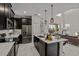 Modern kitchen with stainless steel appliances, a large island, pendant lighting, and dark cabinets at 718 Whistling Straits Blvd, Davenport, FL 33896
