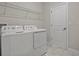 Bright laundry room with white washer and dryer, white walls and tile flooring, plus wire rack at 718 Whistling Straits Blvd, Davenport, FL 33896
