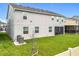 A view of the backyard with a well-maintained lawn, screened-in lanai and newer AC system at 7641 Modica St, Clermont, FL 34714