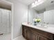 Bathroom boasts a double vanity with white countertops, wood cabinets, and a shower at 7641 Modica St, Clermont, FL 34714