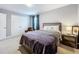 Comfortable bedroom featuring a bed with a gray headboard, closet, and side table with lamp at 7641 Modica St, Clermont, FL 34714