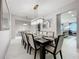 Elegant dining room with a long table set for ten, modern chandelier, and access to the kitchen at 7641 Modica St, Clermont, FL 34714