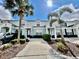 Charming townhome featuring a light blue facade, black door, and lush landscaping with mature palm trees at 7670 Otterspool St, Kissimmee, FL 34747