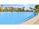 Beautiful large pool surrounded by palm trees, lounge chairs, and community buildings at 8012 Lost Shaker Ln, Kissimmee, FL 34747