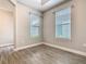 A vacant bedroom with wood-look tile floors, two windows, and baseboard trim at 806 Via Como St, Poinciana, FL 34759