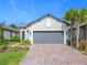 Charming home featuring a gray garage door, brick driveway, and a well-maintained lawn at 806 Via Como St, Poinciana, FL 34759
