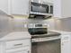 Close up of stainless steel oven and microwave with a decorative backsplash and white cabinets at 806 Via Como St, Poinciana, FL 34759