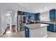 Bright kitchen with a large island, stainless steel appliances, mosaic backsplash, and blue cabinets at 923 Tramells Trl, Kissimmee, FL 34744