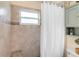 Cozy bathroom with tiled walls, shower with curtain, and storage cabinet with shelving at 9559 Dubois Blvd, Orlando, FL 32825