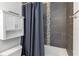 Bathroom showcasing sleek gray tiling and a shower-tub combo with a neutral shower curtain at 9559 Dubois Blvd, Orlando, FL 32825