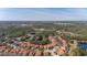 An aerial view of a neighborhood with orange roofed homes, surrounded by lush green trees and a distant highway at 113 Tiger Lily Ct, Davenport, FL 33837