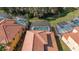 Aerial view of homes featuring screened-in pools and red-tiled roofs with verdant landscaping and a sunny sky at 113 Tiger Lily Ct, Davenport, FL 33837