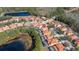 Aerial view of a residential neighborhood, near a lake, featuring homes with orange roofs and screened-in pools at 113 Tiger Lily Ct, Davenport, FL 33837
