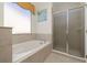 Bright bathroom featuring a tiled bathtub, a glass shower door, and a framed window with natural light at 113 Tiger Lily Ct, Davenport, FL 33837