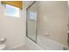 Bathroom with a bathtub/shower with glass door, toilet, and a window with a blind at 113 Tiger Lily Ct, Davenport, FL 33837