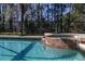 Close up of a pool with water feature and a screened-in lanai with backyard trees in the distance at 113 Tiger Lily Ct, Davenport, FL 33837