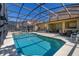 Large screened in pool area with waterfall feature and lounge chairs at 113 Tiger Lily Ct, Davenport, FL 33837