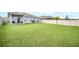 Expansive fenced backyard with lush green lawn, patio, and tropical palm creates a private outdoor oasis at 1185 Catskill Dr, Haines City, FL 33844