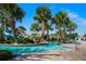 Community pool area showcases clear blue water, palm trees, slide, lounge chairs and tropical scenery at 1646 Moon Valley Dr, Davenport, FL 33896