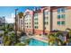 Stunning view of the hotel's exterior, complemented by lush palm trees and a sparkling swimming pool at 3000 Maingate Ln # 205, Kissimmee, FL 34747