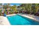 A beautiful turquoise swimming pool area is surrounded by greenery and palm trees with lounge chairs at 3000 Maingate Ln # 205, Kissimmee, FL 34747