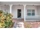 Welcoming front porch with white pillars and railing, leading to an open front door, and adorned with neat landscaping at 318 Rock Springs Dr, Poinciana, FL 34759