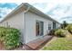 Home's rear exterior showing a brick patio, sliding glass doors, lush plantings and a green lawn under a partly cloudy sky at 318 Rock Springs Dr, Poinciana, FL 34759