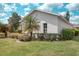Beautiful side view of the home featuring green lawn, lush landscaping, and an architectural roof under blue sky at 318 Rock Springs Dr, Poinciana, FL 34759