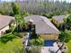 An aerial view shows this house with lush landscaping and a brick paver driveway, nestled among palm trees at 400 Indian Wells Ave, Poinciana, FL 34759