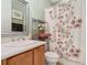 Well-lit bathroom with wood vanity, matching framed mirror and coordinated floral shower curtain at 400 Indian Wells Ave, Poinciana, FL 34759