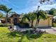 Charming home with a two-car garage, a brick driveway, lush landscaping, and mature palm trees in the front yard at 400 Indian Wells Ave, Poinciana, FL 34759