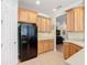 Functional kitchen with tile flooring, wood cabinets, a black refrigerator, and an adjacent pantry at 400 Indian Wells Ave, Poinciana, FL 34759