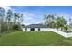 Back exterior of a one story white house with gray roof surrounded by green lawn and trees at 41 Peterlee Ct, Kissimmee, FL 34758