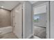 A bright bathroom leads to a bedroom, featuring a tiled shower over tub, a toilet, and neutral-toned floors at 41 Peterlee Ct, Kissimmee, FL 34758