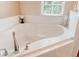A relaxing, oversized bathtub is surrounded by white tile and natural light at 4925 Poolside, St Cloud, FL 34769