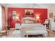 Comfortable bedroom boasts red accent wall, ceiling fan, bench and floral bedding at 4925 Poolside, St Cloud, FL 34769